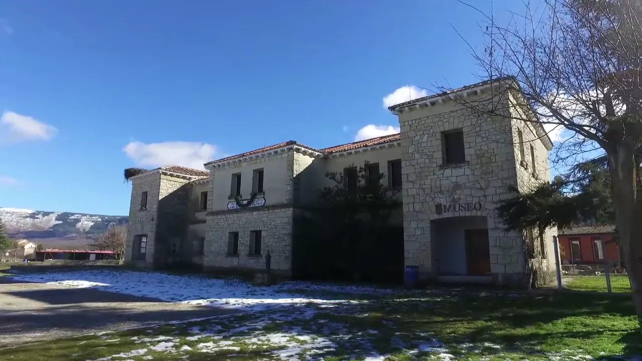Fotografía exterior del edificio principal del museo en Arcones, con muros de piedra clara, tejados de teja árabe y un entorno despejado con restos de nieve.