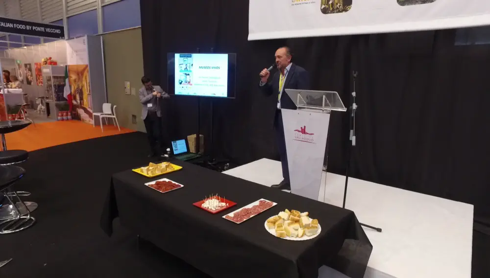 Presentación oficial de Museos Vivos el domingo 25 en la feria Intur con mesa de productos gastronómicos en primer plano.