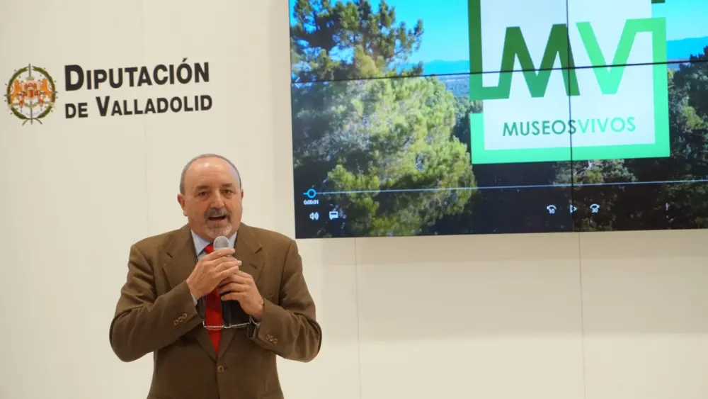 Ponente hablando con un micrófono durante la presentación del proyecto Museos Vivos frente a una pantalla con el logotipo oficial.